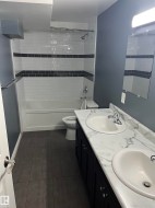 Dual vanity with white undermount sinks, a marble-patterned countertop, and dark cabinetry - 