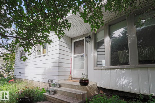 White horizontal siding exterior with a concrete front stoop, storm door, and prominent front window - 21 Burlington Avenue, Spruce Grove, AB 