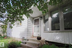 White horizontal siding exterior with a concrete front stoop, storm door, and prominent front window - 
