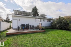 Rear exterior with solar panels, a wooden deck, and a grass lawn - 