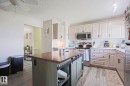 Kitchen featuring wood-finish flooring, an expansive island with storage, white cabinetry, stainless steel appliances, and ceiling fan - 21 Burlington Avenue, Spruce Grove, AB 