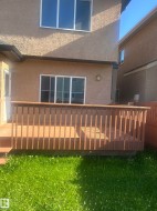 Stucco exterior featuring a wooden deck with railing, sliding glass door, and upper-level windows - 