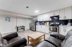 Kitchenette featuring white cabinetry, stainless steel appliances, black marble-look backsplash, and wood-finish flooring - 