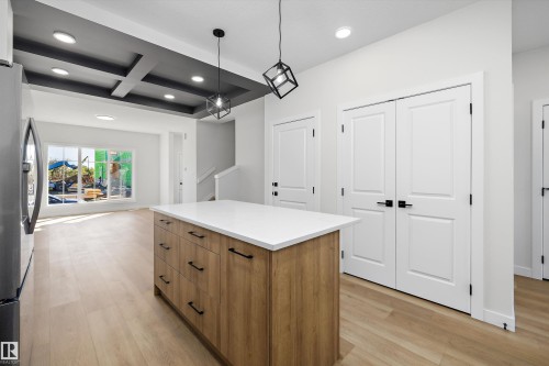 Kitchen island with wood-finish cabinetry and white countertop - 960 Elderberry Landing Nw, Edmonton, AB 