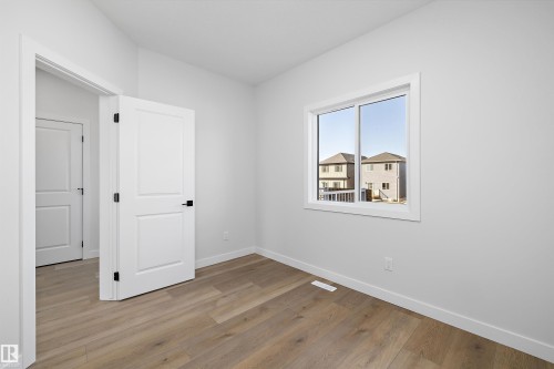 Wood-finish flooring, white trim, and a white interior door with matte black hardware - 960 Elderberry Landing Nw, Edmonton, AB 