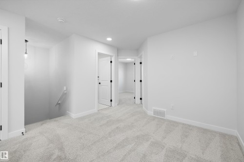 Recessed ceiling lighting, white walls, white doors with black hardware, light gray carpet, and a modern pendant light fixture - 960 Elderberry Landing Nw, Edmonton, AB 