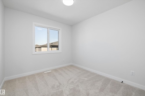 Light grey wall paint and light grey carpeting, with a double-paned window and a flush-mount ceiling light - 960 Elderberry Landing Nw, Edmonton, AB 