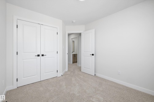 Neutral tone wall paint, light-colored carpet, white interior door, white bi-fold closet doors, matte black hardware - 960 Elderberry Landing Nw, Edmonton, AB 