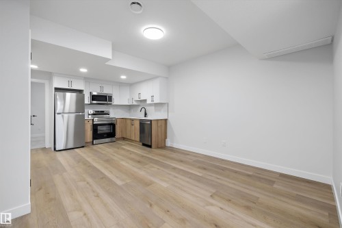 Modern kitchen with stainless steel appliances, white cabinetry, wood-finish flooring, and recessed lighting - 960 Elderberry Landing Nw, Edmonton, AB 