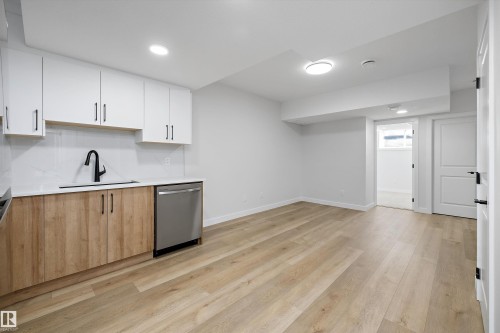 Kitchenette with white upper cabinetry and wood-finish lower cabinetry, solid surface countertops, and stainless steel appliances - 960 Elderberry Landing Nw, Edmonton, AB 