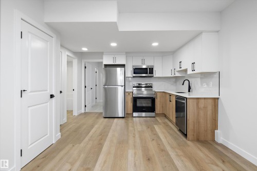 Modern kitchen with stainless steel appliances, light wood-finish flooring, white upper cabinetry, light wood-finish lower cabinetry, and recessed lighting - 960 Elderberry Landing Nw, Edmonton, AB 