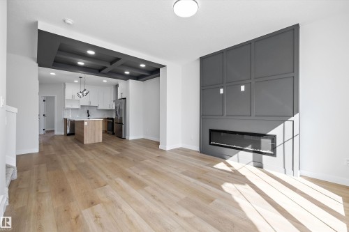 Wood-finish flooring throughout, feature wall with integrated linear fireplace, coffered ceiling, pendant lighting, and stainless steel appliances - 960 Elderberry Landing Nw, Edmonton, AB 
