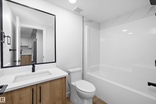 Bathroom featuring a wood-finish vanity with a white countertop, rectangular undermount sink, and black fixtures - 960 Elderberry Landing Nw, Edmonton, AB 