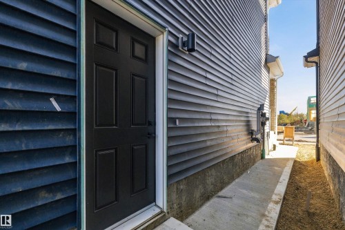 Black six-panel exterior door with white trim and a wall-mounted light fixture - 960 Elderberry Landing Nw, Edmonton, AB 