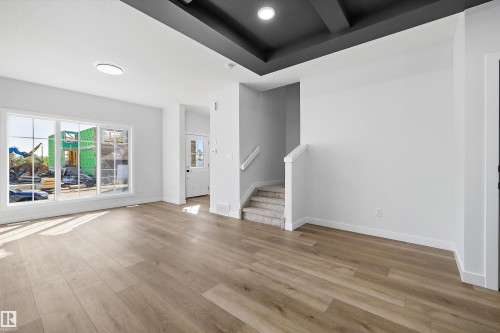 Expansive room featuring wide plank wood-finish flooring, large multi-pane windows, and a coffered ceiling with recessed lighting - 960 Elderberry Landing Nw, Edmonton, AB 
