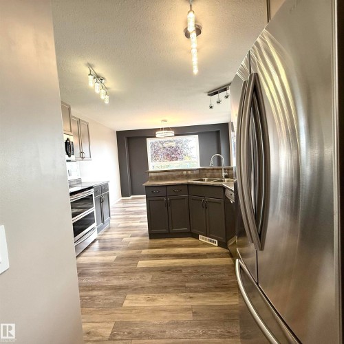 Wood-finish flooring, stainless steel appliances, dark cabinetry, and recessed lighting fixtures - 910 Oakland Boulevard, Devon, AB 