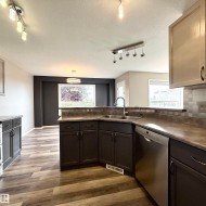 Kitchen featuring stainless steel appliances, dark wood-finish cabinetry, and wood-finish flooring - 