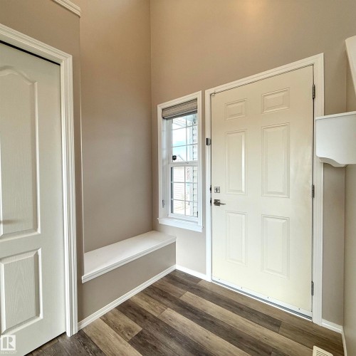Built-in bench seating, wood-finish flooring, paneled entry door, and a window with blinds - 910 Oakland Boulevard, Devon, AB 