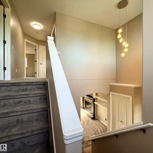 Multi-level interior featuring a contemporary pendant light fixture, archway, and built-in shelving - 910 Oakland Boulevard, Devon, AB 