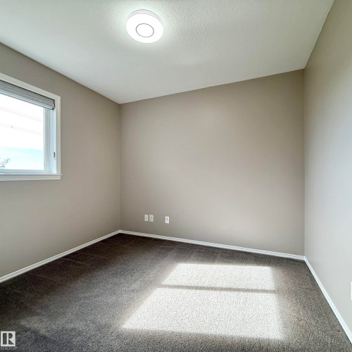 Carpeted flooring, neutral wall color, window with roller shade, and ceiling-mounted light fixture - 910 Oakland Boulevard, Devon, AB 