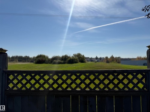 Wood fence with lattice detail, showcasing a green expanse beyond - 910 Oakland Boulevard, Devon, AB 
