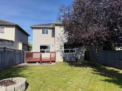Expansive backyard featuring a manicured lawn, stone fire pit, and wood-finish deck - 910 Oakland Boulevard, Devon, AB 