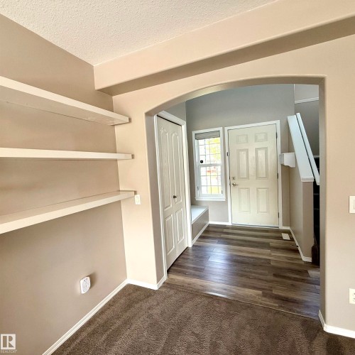 Archway entry featuring built-in shelving, wood-finish flooring, built-in window seating, and a paneled front door - 910 Oakland Boulevard, Devon, AB 