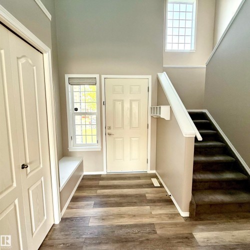 Two-story entryway with wood-finish flooring, a built-in bench, and a paneled front door - 910 Oakland Boulevard, Devon, AB 