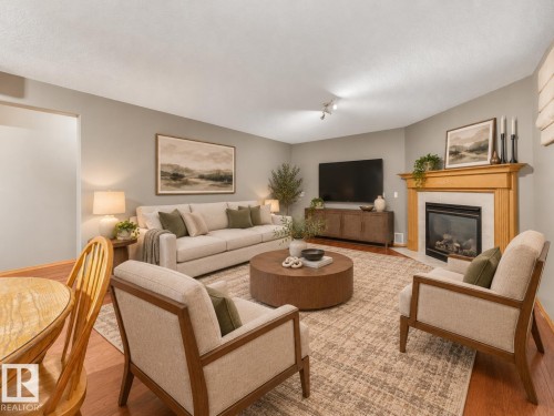 Hardwood flooring, corner fireplace with wood mantel and tile surround, recessed lighting, and wall-mounted track lighting - 1271 Ormsby Lane Nw, Edmonton, AB 