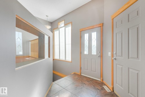 Entryway featuring tile flooring, a paneled door with decorative glass inserts, and wood-trimmed windows - 1271 Ormsby Lane Nw, Edmonton, AB 