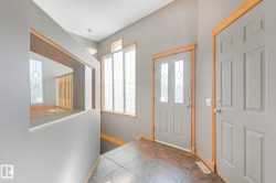 Entryway featuring tile flooring, a paneled door with decorative glass inserts, and wood-trimmed windows - 