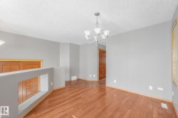 Wood-finish flooring, neutral gray walls, and a multi-arm chandelier - 