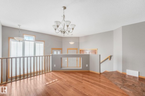 Vaulted ceiling, wood-finish flooring, two large windows, built-in railing, and a decorative chandelier - 1271 Ormsby Lane Nw, Edmonton, AB 