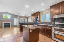 Kitchen featuring wood cabinetry, stainless steel appliances, and a central island with a granite-style countertop - 