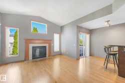 Vaulted ceiling, fireplace with wood mantel and tile surround, wood-finish flooring, sliding glass door, and track lighting fixture - 
