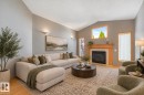 Vaulted ceiling with wall sconces, wood-finish flooring, fireplace with wood mantel and surround, and multiple windows with wood trim - 1271 Ormsby Lane Nw, Edmonton, AB 