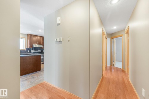Hardwood-finish flooring, recessed ceiling lighting, wood trim doorways, and a partial view of kitchen cabinetry - 1271 Ormsby Lane Nw, Edmonton, AB 