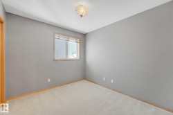 Wall-to-wall carpeting, neutral wall color, and a single window with wood-finish trim - 