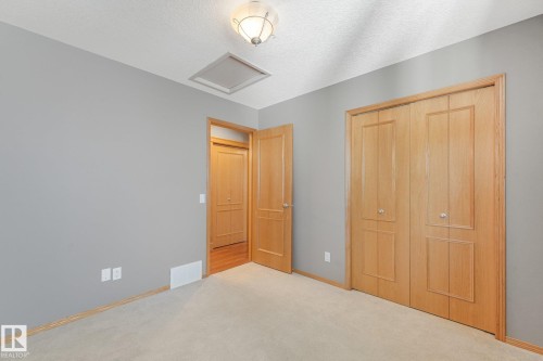 Neutral gray walls, beige carpeting, wood-finish doors, and a flush-mount ceiling light fixture - 1271 Ormsby Lane Nw, Edmonton, AB 