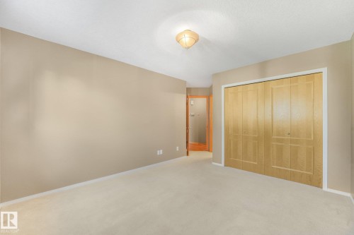 Neutral-toned walls, light-colored carpeting, flush-mount ceiling fixture, and wood-finish bi-fold closet doors - 1271 Ormsby Lane Nw, Edmonton, AB 