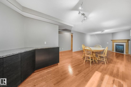 Wood-finish flooring, built-in cabinetry with stone countertop, recessed lighting, and a fireplace with a wood-finished mantel - 1271 Ormsby Lane Nw, Edmonton, AB 
