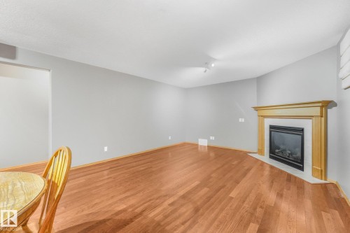 Wood-finish flooring, corner fireplace with wood mantel, and track lighting - 1271 Ormsby Lane Nw, Edmonton, AB 