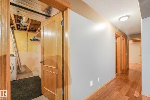 Hardwood-finish flooring extending through the hallway, light-toned wall paint, and wooden door frames - 1271 Ormsby Lane Nw, Edmonton, AB 