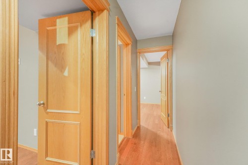 Hardwood flooring throughout the hallway with light wood trim and paneled doors - 1271 Ormsby Lane Nw, Edmonton, AB 