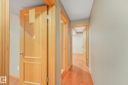Hardwood flooring throughout the hallway with light wood trim and paneled doors - 