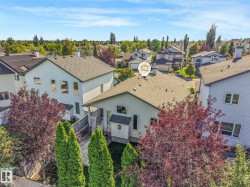Gabled roofline, light-colored siding, multiple windows, and mature trees on the property - 