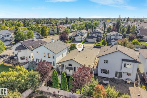 Property featuring a shingled roof, attached deck, mature landscaping, and a paved patio area - 1271 Ormsby Lane Nw, Edmonton, AB 
