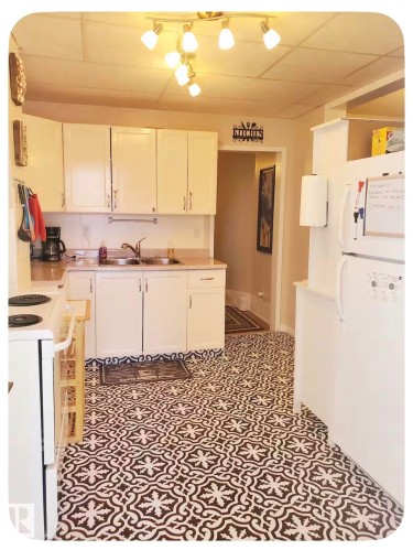 White cabinetry with silver hardware, light-toned countertops, and a track lighting fixture with multiple spotlights - 10649 125 Street Nw, Edmonton, AB 