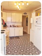 White cabinetry with silver hardware, light-toned countertops, and a track lighting fixture with multiple spotlights - 
