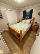 Wood-finish flooring, bi-fold closet doors, window with horizontal blinds, and a flush mount ceiling light - 